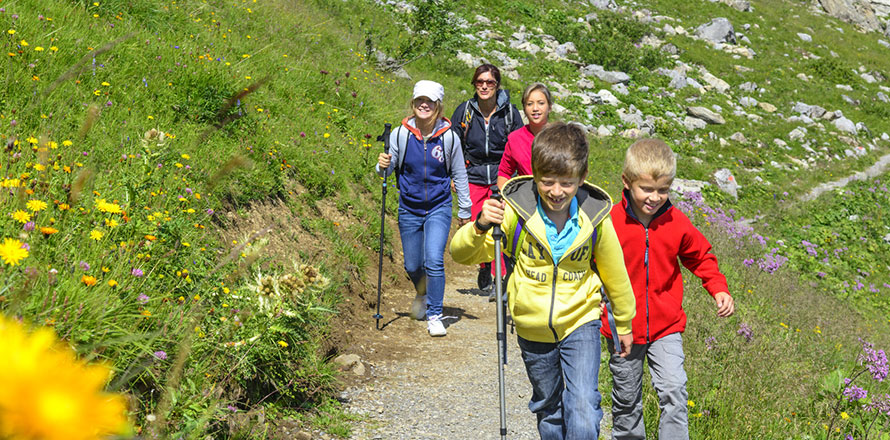 Kinder wandern mit ihren Eltern auf einem Wanderweg 