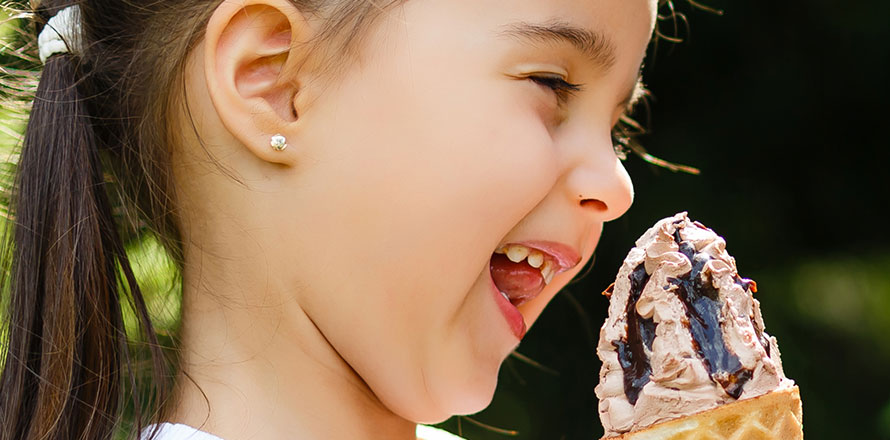 Kleines Mädchen lacht mit Eis in der Waffel in der Hand